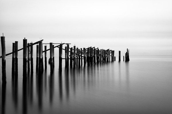 Schwarzweißfoto eines Holzstegs mit viel leerem Wasserraum